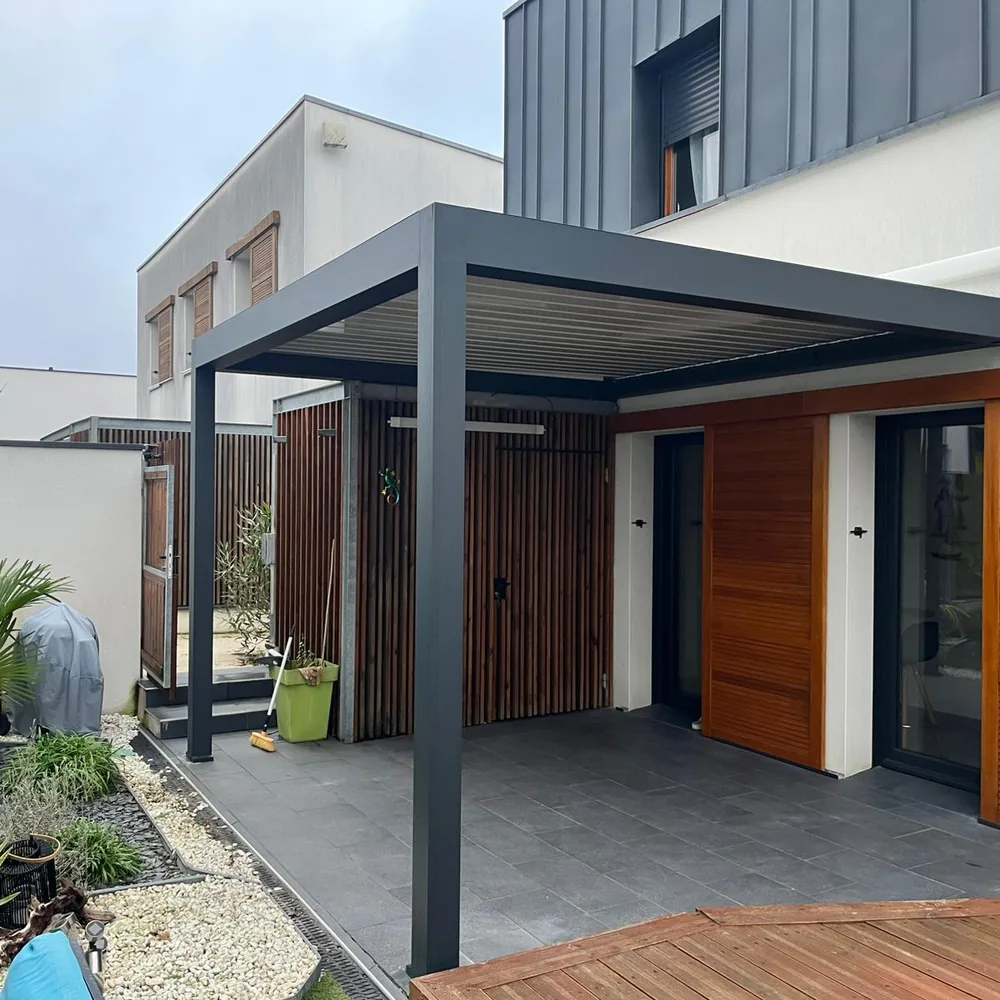 Pergola bioclimatique blanche installée devant une terrasse et un jardin